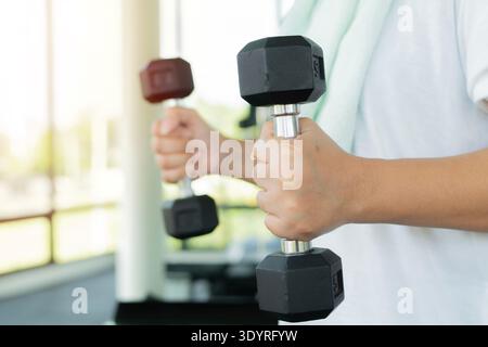 Nahaufnahme, Fitness-Frau, die Hantelgewichte im Fitnessstudio hebt, Übungen mit Hantel macht, Fitness muskulöser Körper, selektiver Fokus Stockfoto