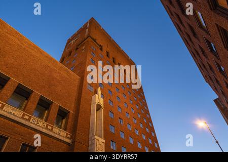Der Blick auf das warme orange Licht taucht das Rathaus von Oslo in der Abenddämmerung vor einem tiefblauen Himmel, ein Leuchtturm der norwegischen Architektur, Oslo, Norwegen. Stockfoto