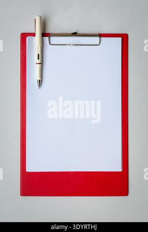 Rote Zwischenablage mit leerem A4-Papier und Stift, isoliert auf weißem Hintergrund. Stockfoto