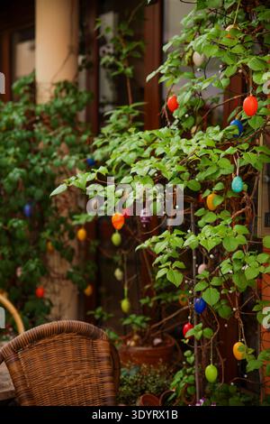 Farbenfrohe Ostereierdekorationen Hängen An Grünen Pflanzenzweigen Auf Der Gemütlichen Terrasse Im Freien Stockfoto