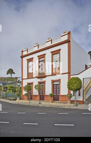 Traditionelles weißes und oranges Haus im Kolonialstil auf La Palma. Authentische spanische Architektur mit Balkonen, Topfpflanzen und klarem Himmel im bac Stockfoto