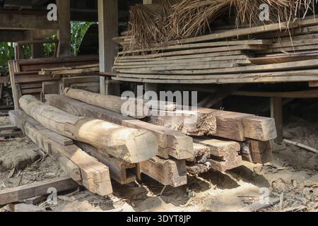 Rustikale Werkstatt gefüllt mit Stapeln von altem Holz, Holzbalken und natürlichen Holzdielen. Die Szene weckt ein Gefühl traditioneller Handwerkskunst und roher Hater Stockfoto