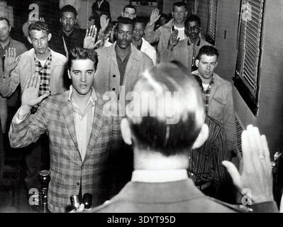 Elvis Presley und ein Zimmer voller junger Männer, die als Teil ihrer Einweisung in Fort Chaffee, Arkansas, in die US Army vereidigt wurden. Datum: 25/03/1958 Stockfoto