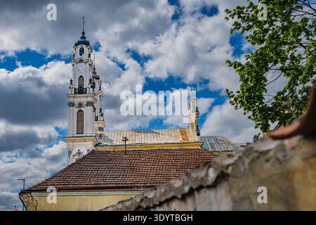 Der elegante weiße barocke Glockenturm der Himmelfahrtskirche (Missionskirche) erhebt sich über den roten Ziegeldächern in Vilnius. Stockfoto