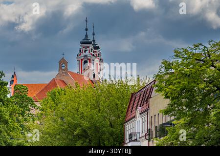 Die markanten rot-weißen Barocktürme der Kirche St. Philipp und St. Jakobus erheben sich über grünen Bäumen in Vilnius, Litauen. Stockfoto