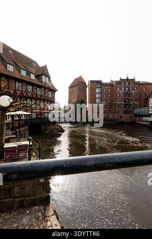 Lüneburg, Niedersachsen, 8. März 2026: Historische Gebäude entlang der Ilmenau mit altem Kran und Uferpromenade in der Altstadt Stockfoto