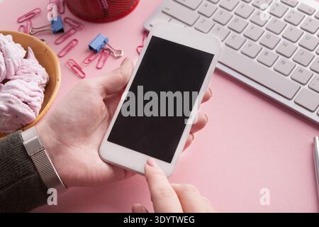Nahaufnahme von Frauenhänden, die ihr Smartphone am Arbeitsplatz halten Stockfoto
