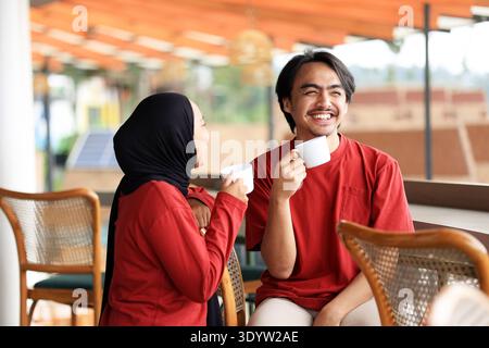 Junges asiatisches indonesisches Paar trinkt Kaffee zusammen im Cafe Restaurant, während er sich unterhält und lächelt Stockfoto