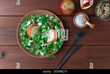 Gesunder gemischter Salat mit Apfelscheiben und Walnüssen serviert auf Holztisch Stockfoto