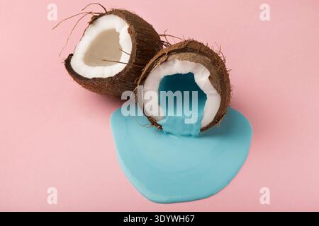 Blaue Farbe läuft aus Kokosnuss auf rosafarbenem Hintergrund Stockfoto