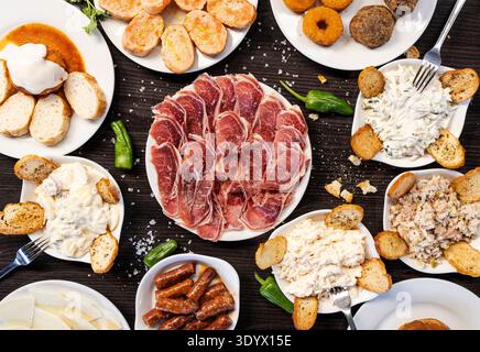 Blick von oben auf eine köstliche spanische Tapas mit Räucherschinken, Salaten und Brot Stockfoto
