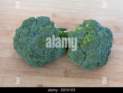 Zwei frische Brokkoli-Köpfe auf hölzernem Schneidebrett. Gesunde grüne pflanzliche Zutat reich an Vitaminen und Ballaststoffen. Stockfoto