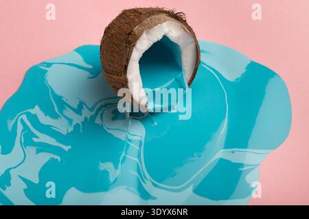 Blaue Farbe läuft aus Kokosnuss auf rosafarbenem Hintergrund Stockfoto