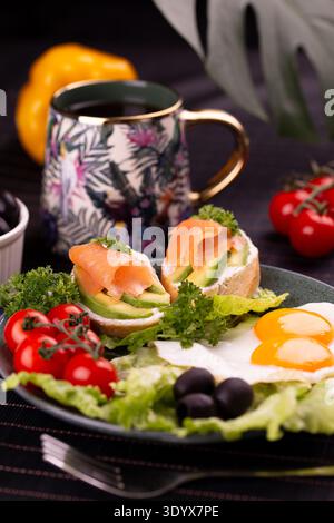 Spiegeleier mit Lachs-Avocado-Toast und Kirschtomaten. Stockfoto