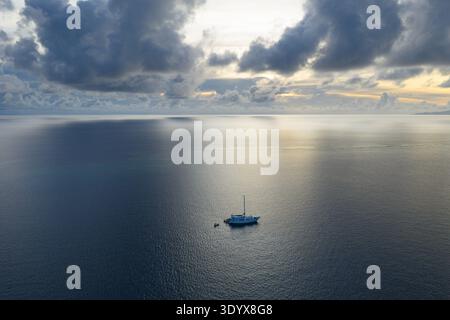 Bei Sonnenaufgang liegt ein kleines Schiff vor Anker in einem abgelegenen Teil von Fidschi. Diese wunderschöne Gegend ist bekannt für ihr warmes, tropisches Klima. Stockfoto