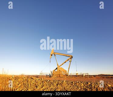 Pumpwagenheber (nickender Esel) in einer Wüste bei Sonnenuntergang. Stockfoto