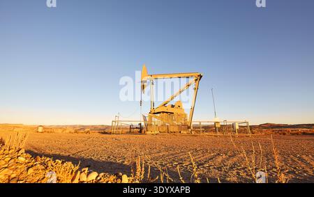 Pumpwagenheber (nickender Esel) in einer Wüste bei Sonnenuntergang. Stockfoto