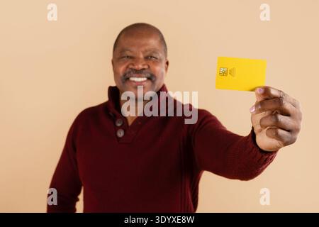 Ein lächelnder afroamerikaner zeigt gelbe Kreditkarte vor der Kamera Stockfoto