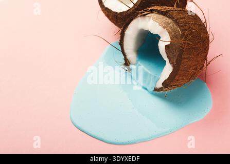 Blaue Farbe läuft aus Kokosnuss auf rosafarbenem Hintergrund Stockfoto