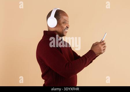 Seitenansicht eines Reifen schwarzen Mannes mit Smartphone und schnurlosen Kopfhörern Stockfoto