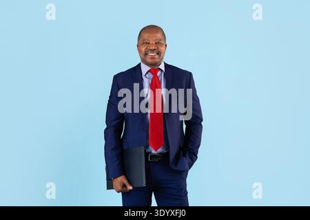 Reifer afroamerikanischer Geschäftsmann, der auf Studiohintergrund eine Mappe hält Stockfoto