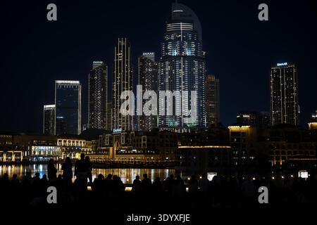 Ein nächtlicher Blick auf die moderne Skyline der Stadt mit hell beleuchteten Wolkenkratzern, die sich über niedrigeren Gebäuden im traditionellen Stil erheben. Im Vorfeld Stockfoto