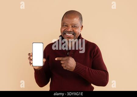 Reifer afroamerikanischer Mann im burgunderroten Pullover, der Smartphone mit leerem Bildschirm hält Stockfoto
