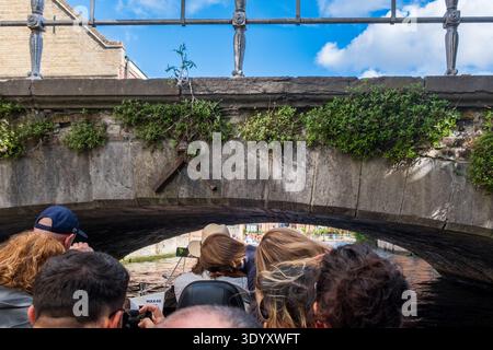 Bootstour auf dem Brügge Kanal unter einem Steinbrückenbogen mit Touristen an Bord, Brügge, Belgien Stockfoto