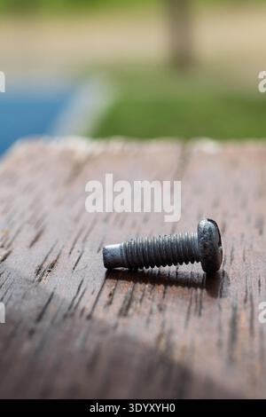 Gebrochene Metallschraube mit abgenommener Spitze auf einer alten strukturierten Holzdiele Stockfoto