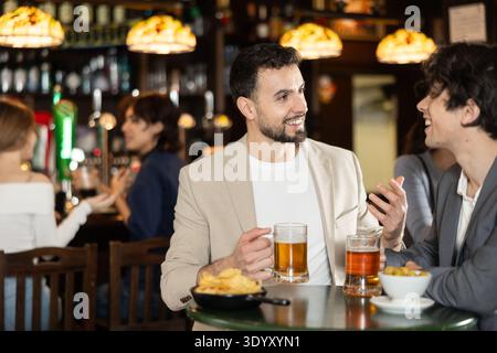 Zwei junge Männer plaudern und trinken Bier an der Bar Stockfoto