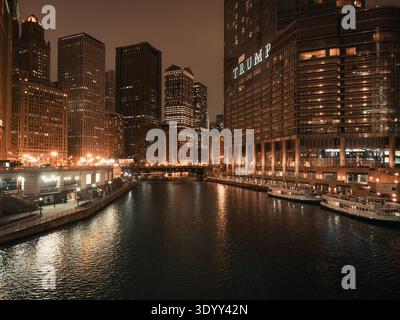 Am Ufer des Chicago River mit Trump International Hotel und Turm, beleuchtet bei Nacht zwischen Wolkenkratzern in der Innenstadt Stockfoto