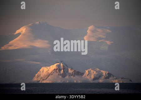 Malerischer Blick am späten Nachmittag auf eine schneebedeckte Landmasse vor dem Hintergrund hoher, schneebedeckter Berge, Portal Point, Antarktis PE Stockfoto