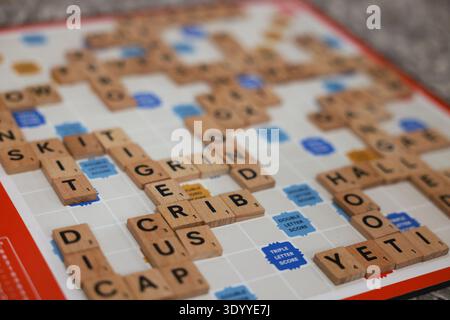 Hölzerne Buchstabenfliesen auf Scrabble Brett bilden Wörter, lehrreiches Wortpuzzle und Vokabelspiel. Englisches Vokabelspiel Stockfoto