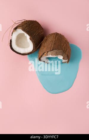 Blaue Farbe läuft aus Kokosnuss auf rosafarbenem Hintergrund Stockfoto