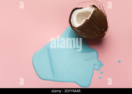 Blaue Farbe läuft aus Kokosnuss auf rosafarbenem Hintergrund Stockfoto
