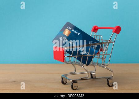 Warenkorb mit Kreditkarte auf blauem Hintergrund Stockfoto