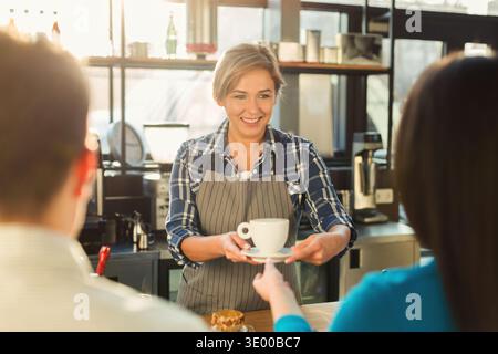 Erfahrener lächelnder Barista, der den Gästen Kaffee zubereitete Stockfoto