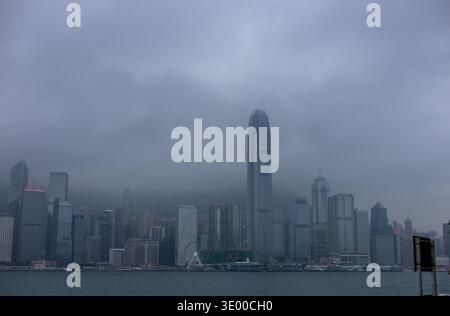 Die Skyline von Hong Kong Island einschließlich zwei International Finance Centre, die von niedrigen Wolken und Nebel gehüllt sind, wie man sie von Tsim Sha TS über den Victoria Harbour sehen kann Stockfoto