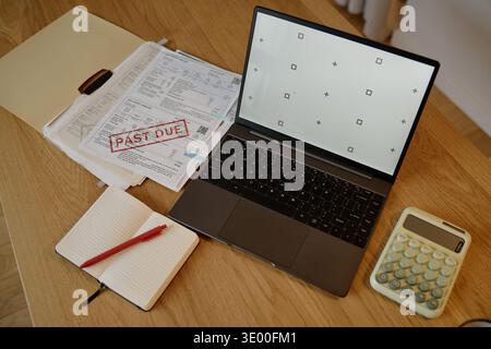Überfällige Rechnungen mit Laptop und Rechner auf dem Schreibtisch zu Hause Stockfoto