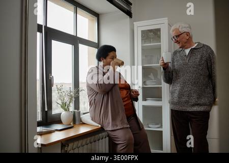 Senior kaukasischer Mann und Schwarze mittleren Alters genießen heiße Getränke drinnen Stockfoto
