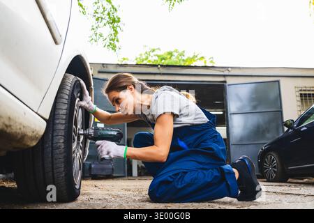 Professioneller weiblicher Mechaniker, der das Fahrzeugrad in der Garage repariert Stockfoto