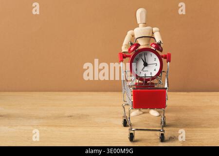 Holzpuppe mit rotem Wecker im Warenkorb Stockfoto
