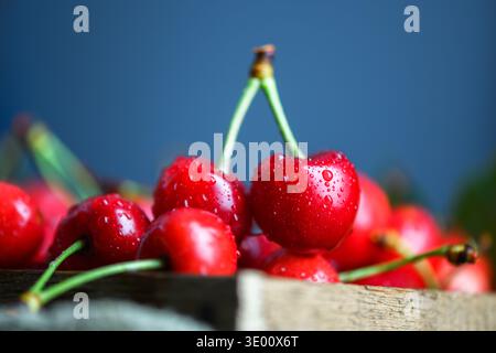 Kirschenstapel mit grünem Blatt auf rustikaler Oberfläche, geringe Tiefe. Frisches süßes Bio-Obst, Sommererntekonzept Stockfoto