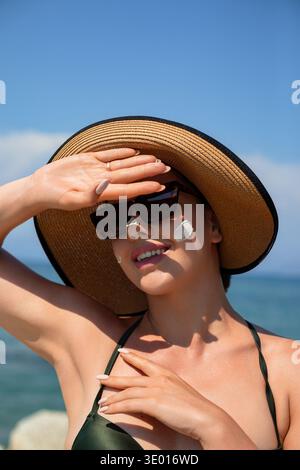 Schöne Frau, die am Strand Sonnencreme auf das Gesicht aufträgt. Sonnencreme. Haut- und Körperpflegekonzept. Frau mit feuchtigkeitsspendender Sonnencreme zum Schutz der Haut Stockfoto