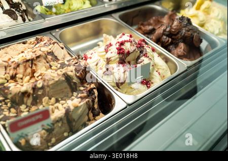 Nahaufnahme verschiedener hausgemachter Eissorten mit Minze mit Schokoladenbanane und nussiger Schokolade in Edelstahlbehältern in einem modernen Gel Stockfoto