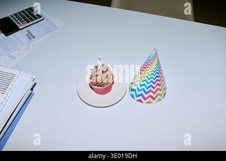 Schokoladen-Cupcake mit Kerze und Partyhut zum Geburtstag im Haus Stockfoto