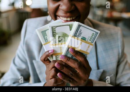 Schwarze Frau mittleren Alters lächelt, während sie uns Dollar-Scheine hält Stockfoto