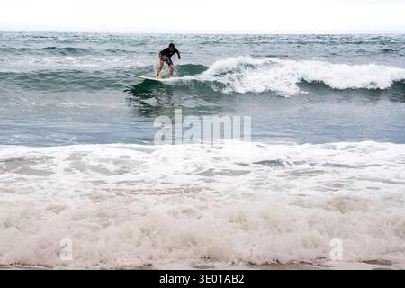 Surfer auf einer Welle in Crackington Haven an der Nordküste von Cornwall, Großbritannien Stockfoto