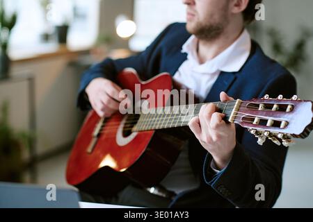 Kaukasischer junger Erwachsener, der tagsüber Akustikgitarre spielt Stockfoto