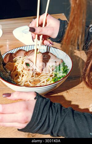 Mann isst Ramen mit Stäbchen. Professionelle Studio-Leuchte Stockfoto